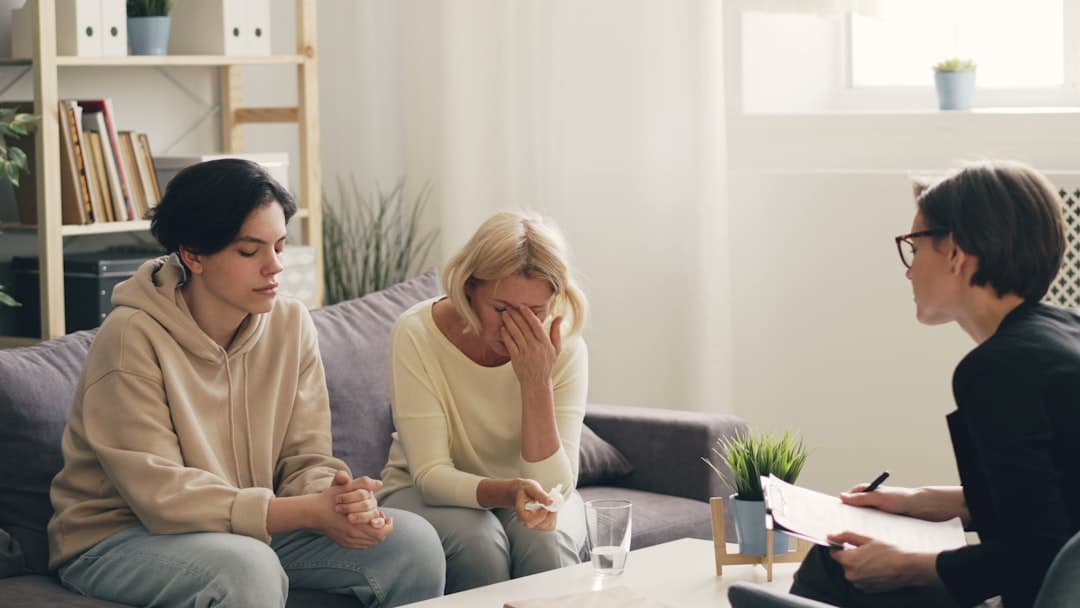 two women sitting on a couch talking to each other. Cover image for: AI Medical Scribe for Mental Health and Psychiatry.