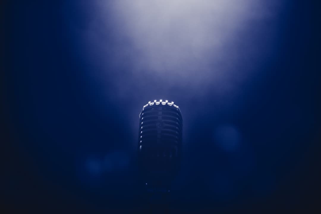 low light stage microphone photography. Cover image for: Medical Transcription in 2026: The Complete Guide for Modern Practices.