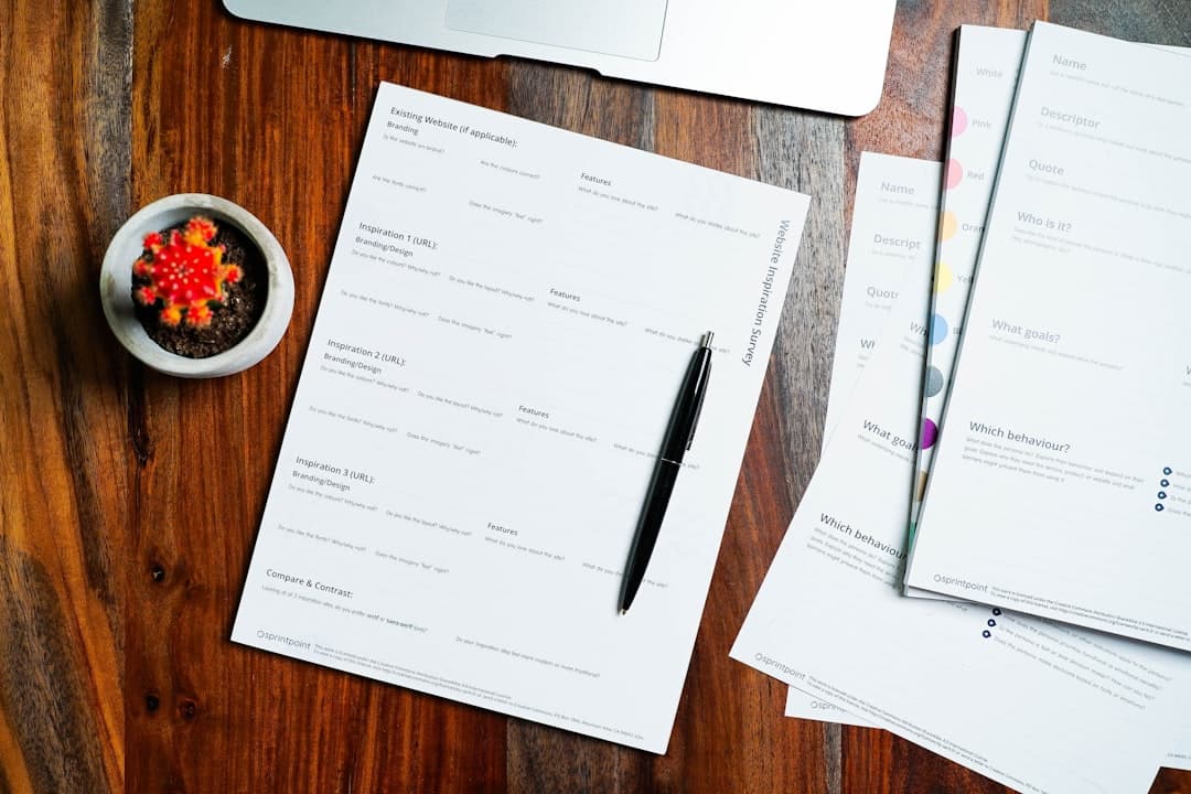 a wooden table topped with papers and a pen. Cover image for: Patient Attitudes Toward AI Recording Their Medical Visits.