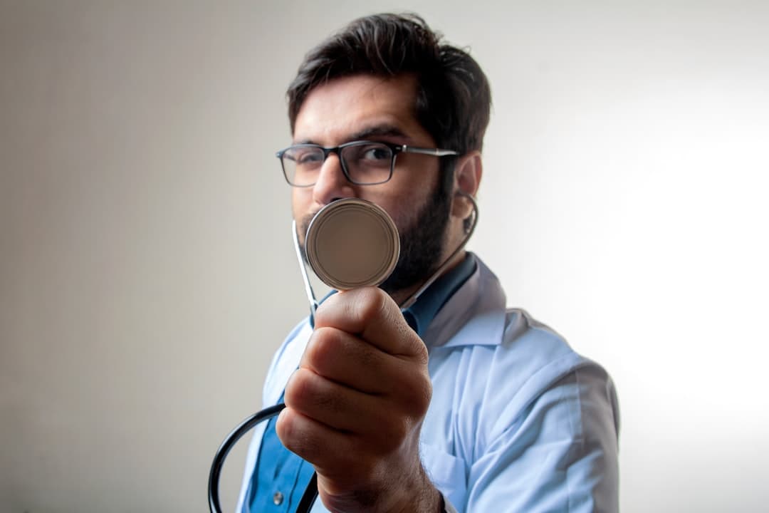 man in blue dress shirt holding black and silver headphones