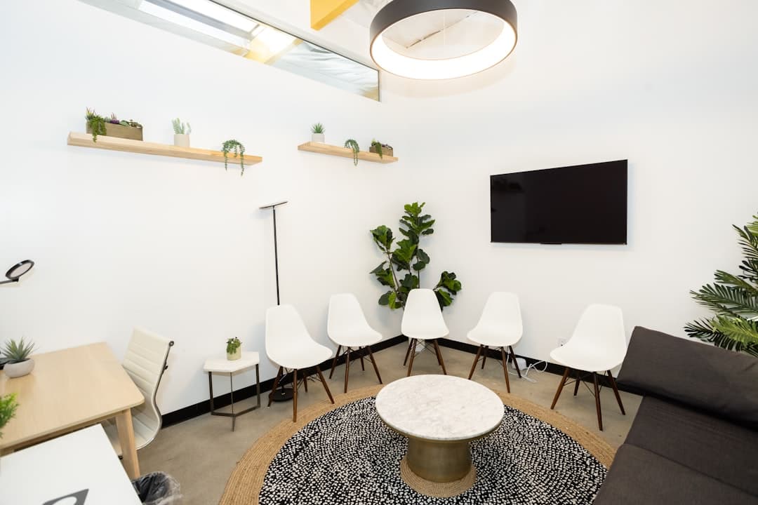 Modern waiting room with white chairs and plants.